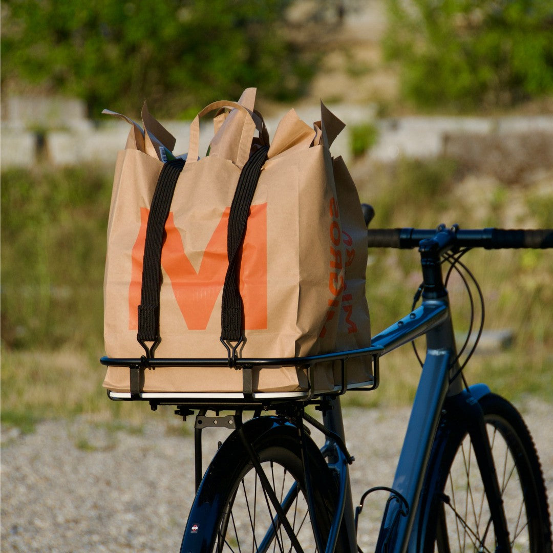 Ein Fahrrad mit dem Velokorb PACKI mit zwei Einkaufstaschen